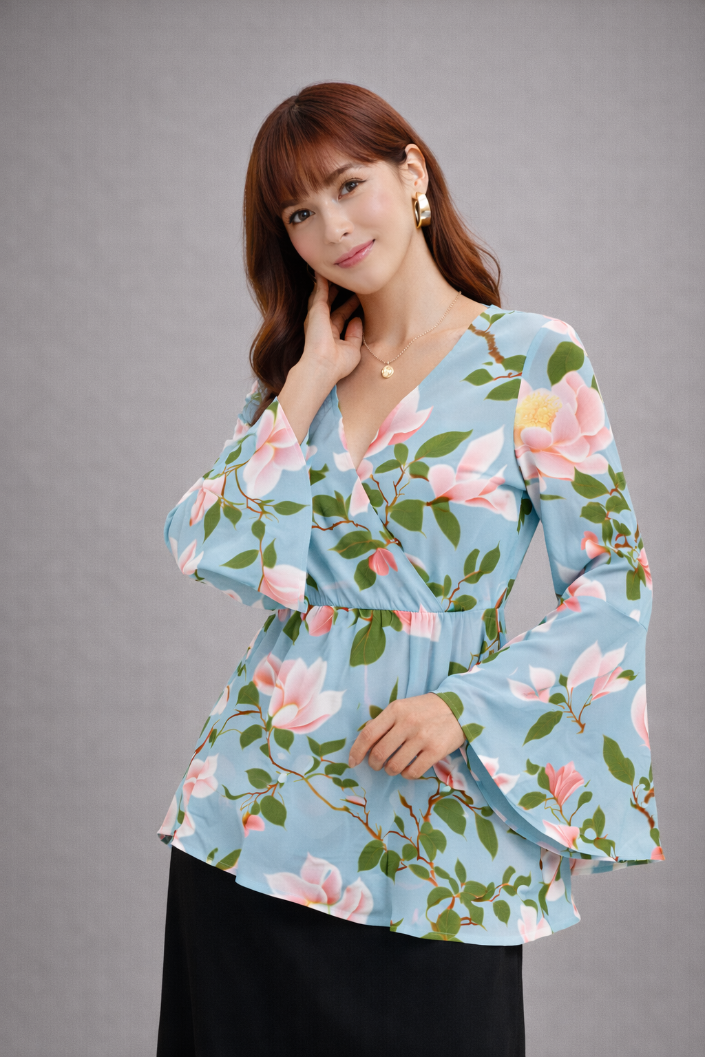 Femme portant une blouse à fleurs sur fond gris