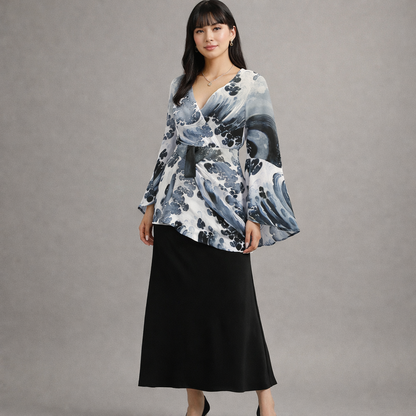 Femme portant une blouse à fleurs et une jupe noire sur fond gris