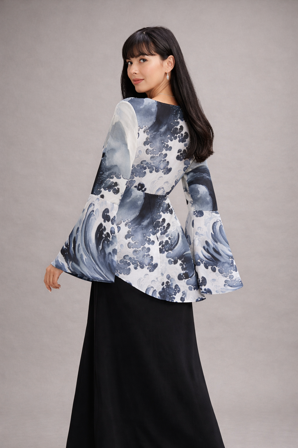 Femme portant une blouse à fleurs à manches évasées sur fond gris